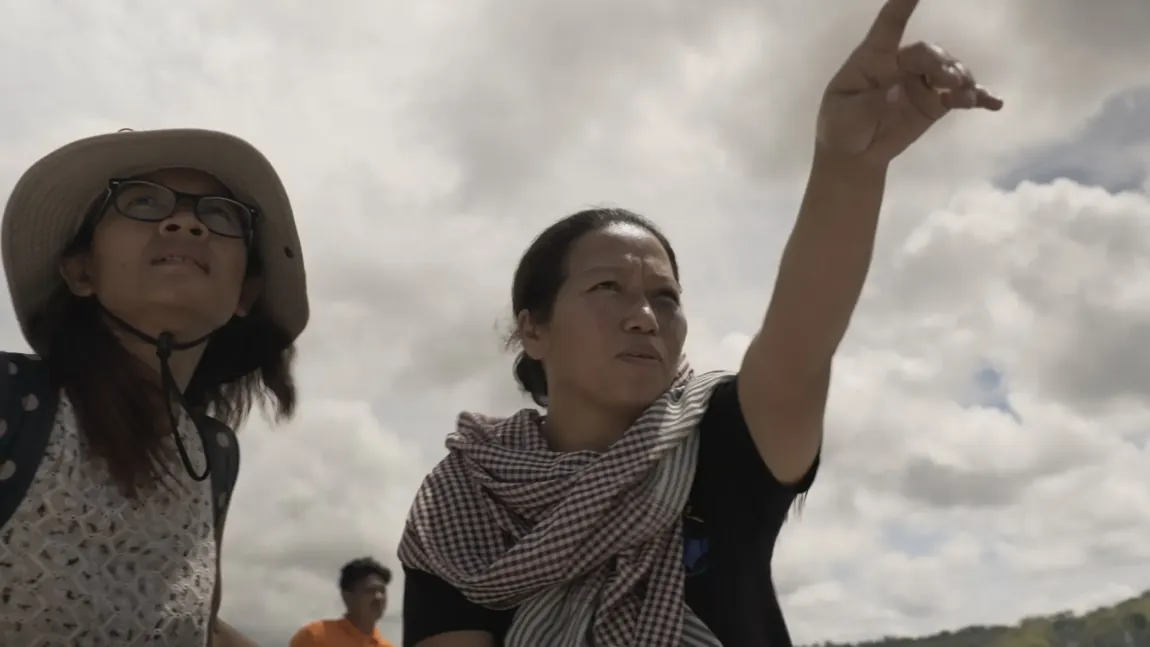 Two women on location, one gesturing toward the distance